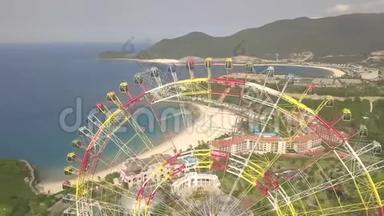无人机在海洋和山体景观的游乐园中观看五颜六色的摩天轮。 大型摩天轮游乐园